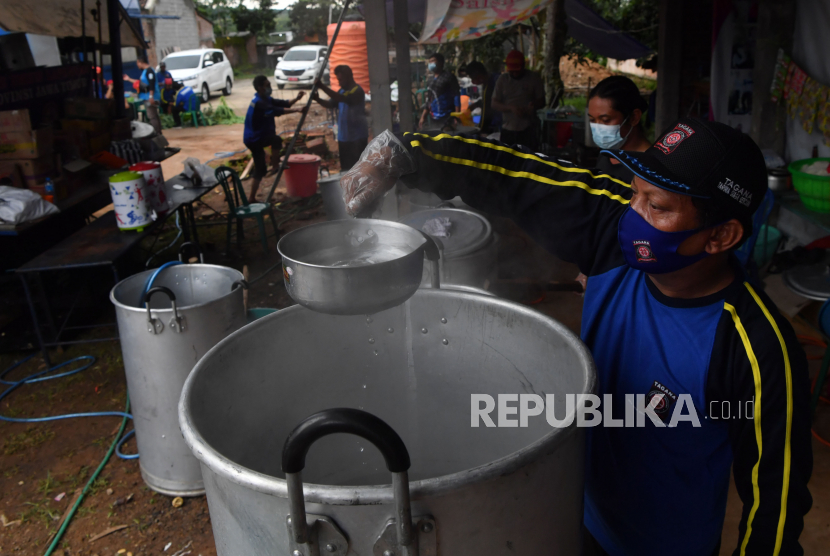 Relawan memasak air di dapur umum tanah longsor di Ngetos, Nganjuk, Jawa Timur, Senin (15/2/2021). Dapur umum tersebut dibuka untuk membantu menyediakan makanan bagi pengungsi tanah longsor dan petugas serta tim SAR yang bertugas. 