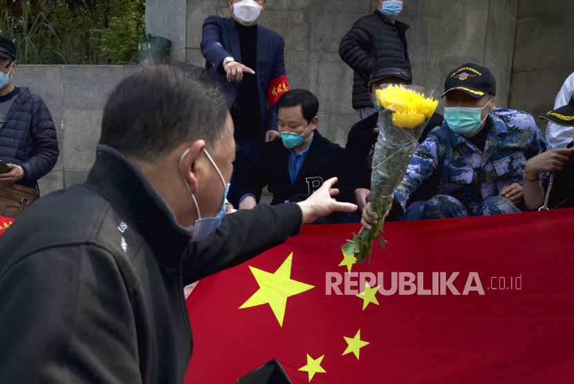 Warga membawa bendera China saat peringatan berkabung nasional untuk para korban Covid-19 di Wuhan, Provinsi Hubei, China, Sabtu (4/4).