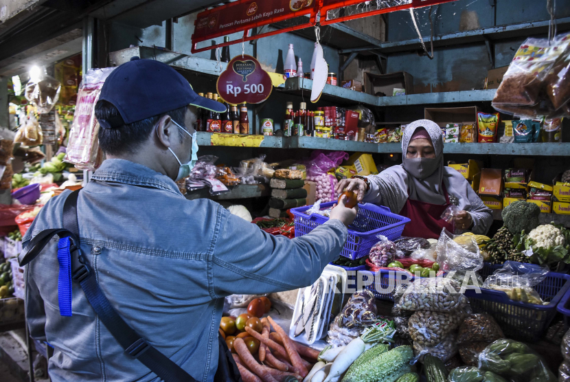 Pedagang mengenakan masker saat melayani pembeli di Pasar Tradisional Cihapit, Jalan Cihapit, Kota Bandung, Ahad (5/4). Pemkot Bandung menyiapkan dana Rp 298 miliar untuk penanganan Covid-19.