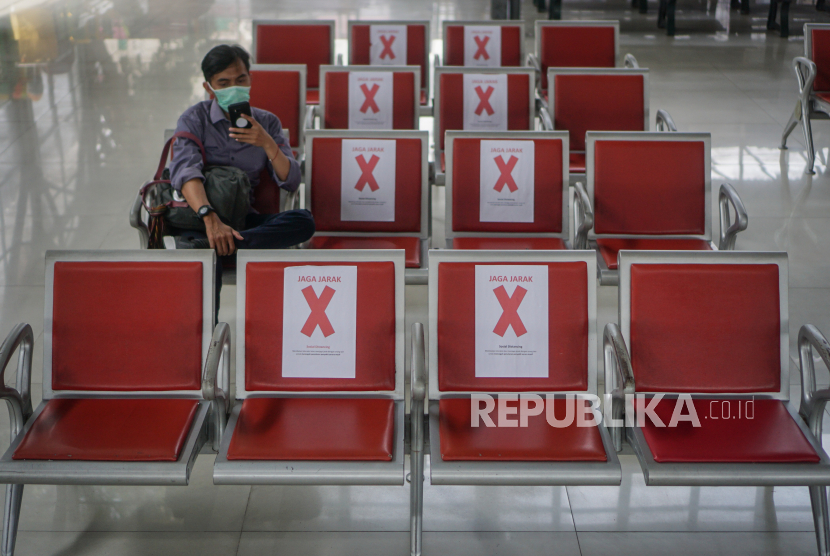 Calon penumpang duduk di kursi tunggu yang diberi penanda jarak aman di Stasiun Purwosari, Solo, Jawa Tengah, Senin (23/3/2020).u 