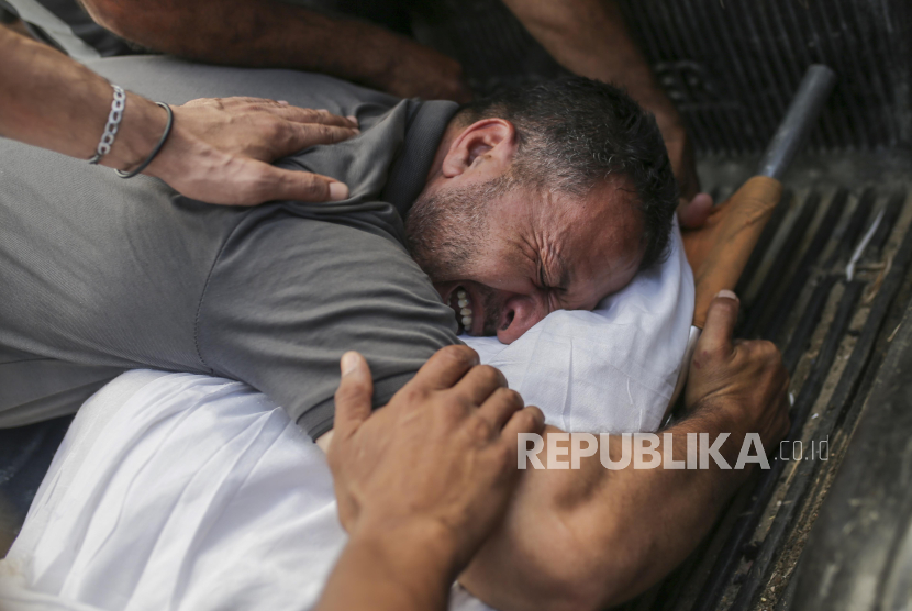 Seorang ayah meratapi dan memeluk jenazah anggota keluarganya yang gugur di RS Al-Aqsa Martyrs, Deir al Balah, Jalur Gaza, Senin, 10 Juni 2024.. Hingga kini, militer Israel terus melakukan genosida.