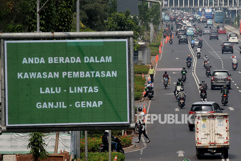 Kendaraan melintas di dekat papan elektronik informasi mengenai kebijakan ganjil-genap di Kawasan Senayan, Jakarta