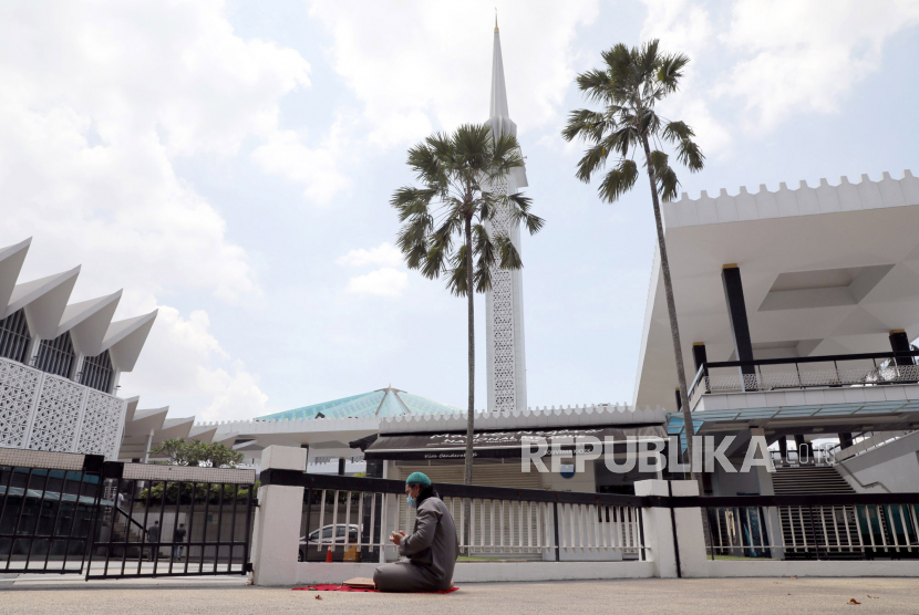 Seorang muslim berdoa di luar Masjid Nasional, Kuala Lumpur, Malaysia, Jumat (15/5). Malaysia melonggarkan aturan larangan sholat jamaahl di masjid-masjid saat pandemi virus corona