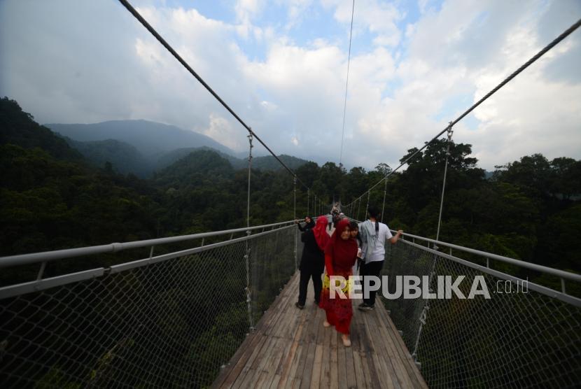 Wisatawan  melintasi  Situ Gunung Suspension Bridge di Taman Nasional Gunung Gede Pangrango, Kadudampit, Sukabumi, Selasa (19/6).