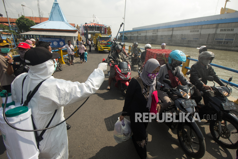 Petugas menyemprotkan larutan disinfektan kepada penumpang yang turun dari kapal KMP Gajah Mada di Penyeberangan Ujung-Kamal, Surabaya, Jawa Timur, Sabtu (28/3/2020). Kegiatan itu untuk mencegah penyebaran Virus Corona (COVID-19)