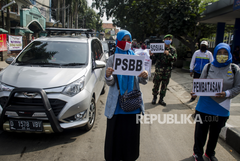 Massa yang tergabung dari ASN, warga, Personil Polisi dan TNI melakukan aksi kampanye Pembatasan Sosial Berskala Besar (PSBB) Kota Bandung di Alun Alun Ujungberung, Bandung, Jawa Barat, Senin (20/4/2020). Aksi tersebut guna mengedukasi dan sosialisasi kepada warga dan pedagang terkait kebijakan penerapan PSBB di Bandung Raya yang dimulai pada Rabu 22 April 2020 sebagai bentuk memutus penyebaran COVID-19