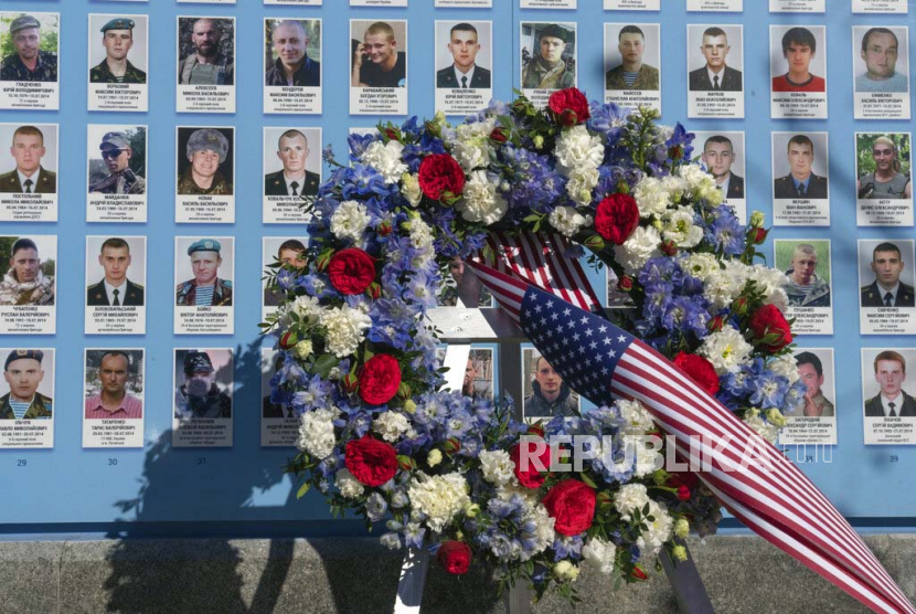 Bunga ditempatkan oleh Presiden Joe Biden di Tembok Peringatan Pembela Ukraina yang Jatuh dalam Perang Rusia-Ukraina dengan foto tentara yang terbunuh di Kyiv, Ukraina, Senin, 20 Februari 2023.