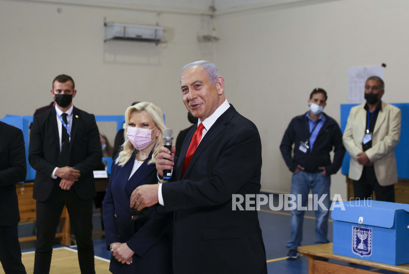  Perdana Menteri Israel Benjamin Netanyahu memberikan pernyataan kepada anggota media saat istrinya Sara berdiri di sampingnya setelah mereka memberikan suara mereka dalam pemilihan umum Israel, di sebuah tempat pemungutan suara di Yerusalem, 23 Maret 2021.