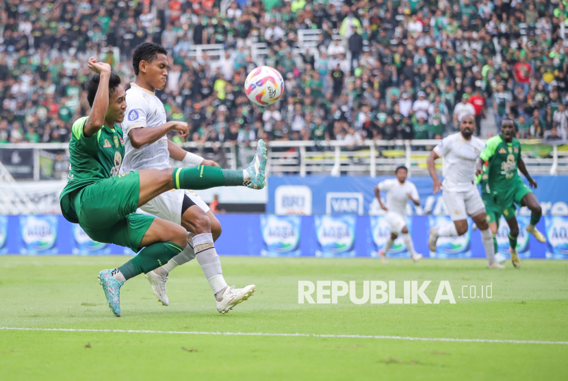 Pesepak bola Persebaya Surabaya Arief Catur Pamungkas (kiri) menendang bola dengan dihadang pesepak bola Arema FC Muhammad Iksan Lestaluhu (kedua kiri) pada pertandingan BRI Liga 1 di Stadion Gelora Bung Tomo, Surabaya, Jawa Timur, Sabtu (7/12/2024). Persebaya mengalahkan Arema FC dengan skor 3-2. 