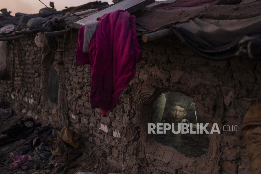  Seorang anak melihat ke luar jendela rumahnya di lingkungan tempat banyak pengungsi internal telah tinggal selama bertahun-tahun, di Kabul, Afghanistan, Selasa, 7 Desember 2021. 