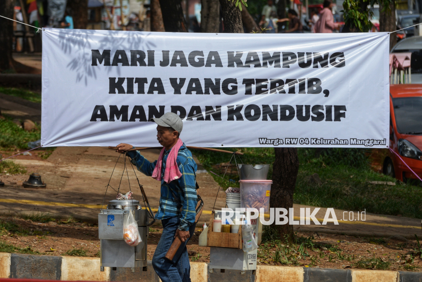 Pedagang melintas di depan spanduk bertuliskan ajakan untuk menjaga perdamaian di Manggarai, Jakarta, Rabu (3/9/2025). Spanduk ajakan untuk menjaga fasilitas umum dan menolak aksi anarkis terpasang di sejumlah titik di Jakarta pasca kerusuhan yang terjadi pada beberapa hari lalu.