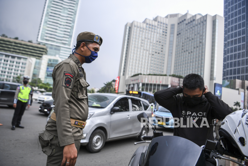 Satpol PP meminta pengendara motor mengenakan masker saat pemeriksaan kepatuhan Pembatasan Sosial Berskala Besar (PSBB) di kawasan Bundaran HI, Jakarta, Senin (13/4/2020). Pemeriksaan tersebut untuk memastikan setiap pengendara mobil dan motor mematuhi aturan PSBB yang diterapkan di DKI Jakarta