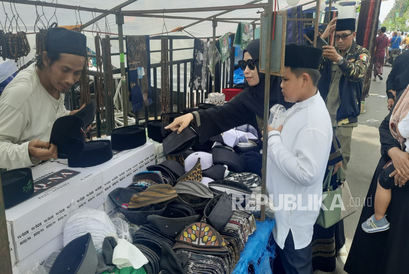 Seorang pedagang asal Klaten, Nur Cholis (40 tahun) berjualan dalam acara Resepsi Puncak Satu Abad Nahdlatul Ulama (NU) sedang berlangsung di Stadion Gelora Delta Sidoarjo, Selasa (7/2/2023). 