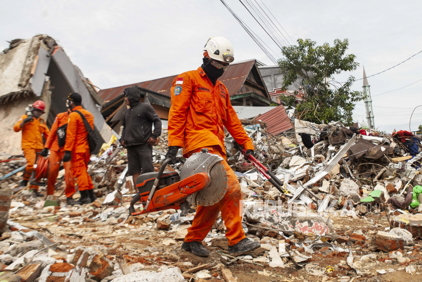  Anggota Pencarian dan Penyelamat Indonesia (BASARNAS) membawa peralatan mereka saat mereka mencari korban di sebuah bangunan roboh yang rusak akibat gempa berkekuatan 6,2 di Mamuju, Sulawesi Barat, Indonesia, 16 Januari 2021. Badan Nasional Penanggulangan Bencana (BNPB) mencatat hingga hari ini, Ahad (17/1/2021), jumlah korban meninggal akibat gempa bumi 6,2 SR di Sulawesi Barat (Sulbar) mencapai 73 orang