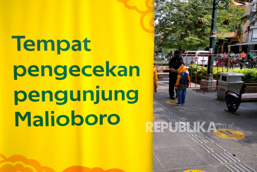 Petugas mengukur suhu tubuh pengunjung sebelum memasuki kawasan wisata Malioboro, Yogyakarta, Ahad (19/7).