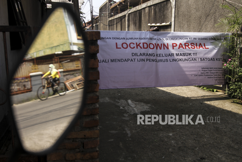 Warga melintas di kawasan lockdown parsial di Beji, Depok, Jawa Barat, Sabtu (3/7/2021). Pemerintah Kota Depok menetapkan Kota Depok masuk kedalam zona merah dengan kasus positif COVID-19 mencapai 9575 orang pada update terakhir tanggal 2 Juli 2021. 