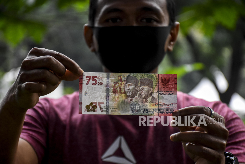 Warga menunjukkan uang baru pecahan Rp75.000 (ilustrasi)