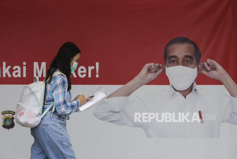  Seorang wanita berjalan melewati spanduk yang menunjukkan Presiden Indonesia Joko Widodo mengenakan masker pelindung wajah, di Jakarta, Indonesia, Senin (14/9). (ilustrasi)
