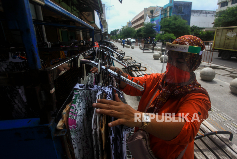 Wati, pedagang kaki lima (PKL) Malioboro dengan masker dan pelindung di wajahnya menata pakaian daganganya di kawasan Jalan Malioboro, Yogyakarta. Sejak satu pekan terakhir, sejumlah PKL Malioboro mulai kembali berjualan setelah tutup sejak pertengahan bulan Maret 2020 akibat merebaknya wabah Covid-19.
