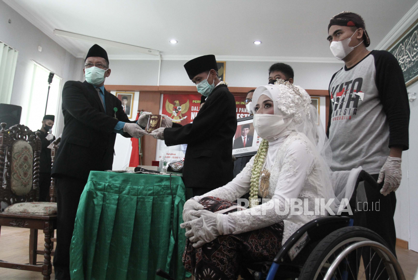 Penghulu menyerahkan buku nikah kepada pengantin saat acara Nikah Gratis di KUA Sewon, Bantul, DI Yogyakarta, Selasa (8/6/2021). Nikah Gratis yang digelar oleh Forum Ta