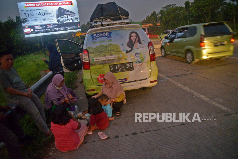 Sejumlah pemudik berbuka puasa sambil beristirahat di KM 102 ruas tol Cikopo-Palimanan, Subang, Jawa Barat, Kamis (28/4/2022). Padatnya sejumlah rest area di sepanjang jalan tol Trans Jawa membuat pemudik memanfaatkan bahu jalan untuk berbuka puasa dan istirahat sejenak.Prayogi/Republika