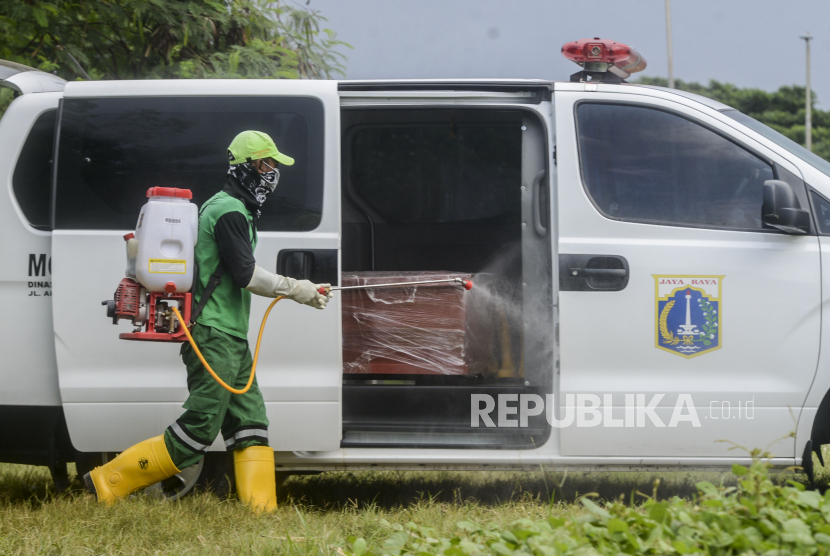 Petugas menyemprotkan cairan disinfektan sebelum membawa peti jenazah pasien suspect Corona ke liang lahat di Tempat Pemakaman Umum (TPU) Tegal Alur, Kalideres, Jakarta, Kamis (26/3). TPU Tegal Alur merupakan salah satu lahan pemakaman yang disediakan oleh Pemerintah Provinsi (Pemprov) DKI Jakarta bagi pasien yang meninggal karena Corona atau Covid-19
