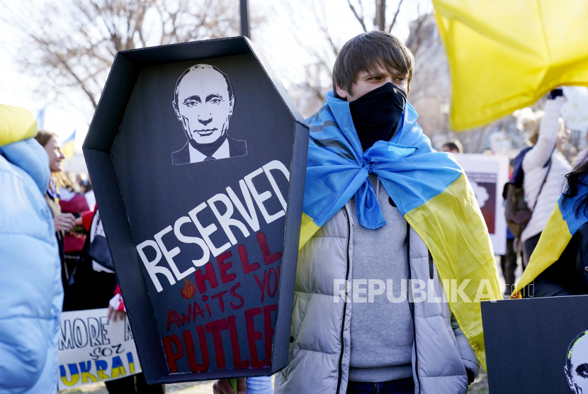 Seorang pria membawa peti mati berisi gambar Presiden Rusia Vladimir Putin saat ia mengambil bagian dalam protes terhadap invasi Rusia ke Ukraina di luar Gedung Putih di Washington, Ahad 27 Februari 2022.