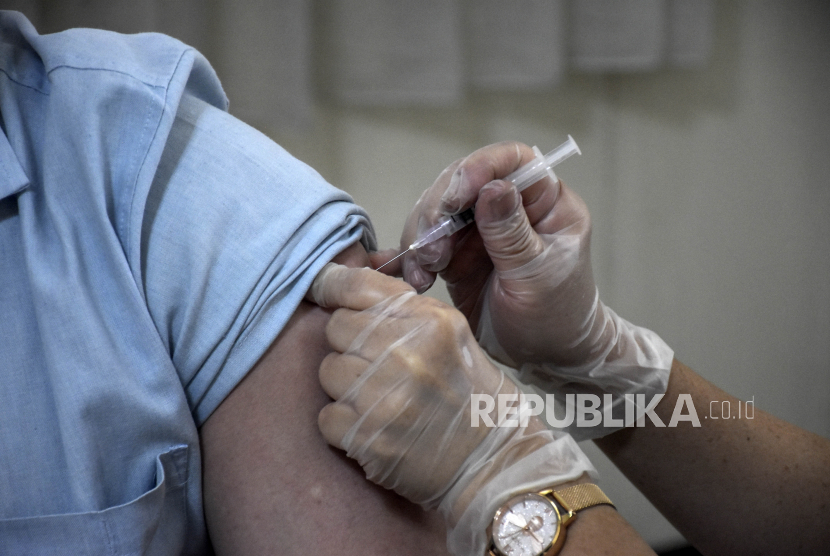 Vaksinator menyuntikkan vaksin Covid-19 dosis keempat ke warga.