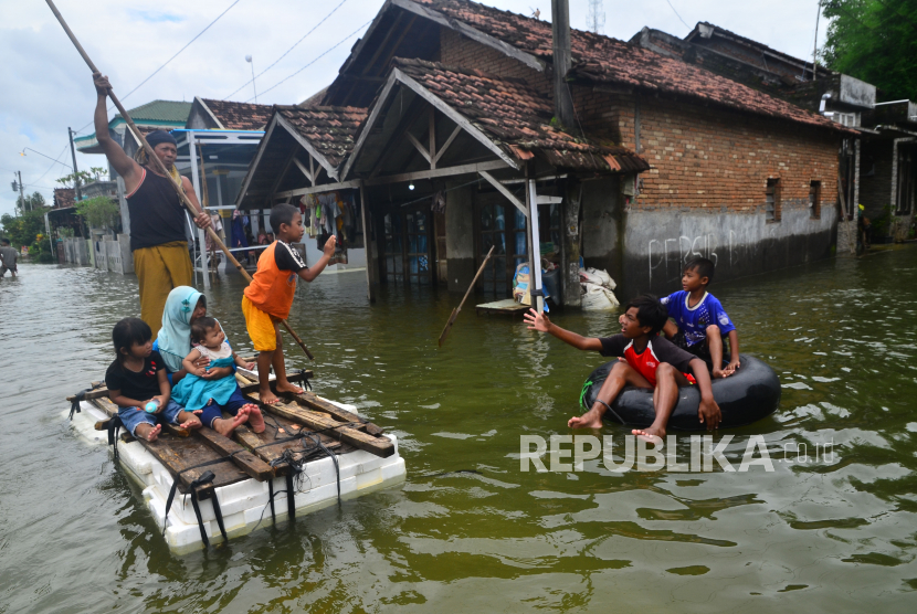 Warga menggunakan ban dan rakit untuk melewati jalan desa yang tergenang banjir di Desa Setroklangan, Kudus, Jawa Tengah, Rabu (3/2/2021). 