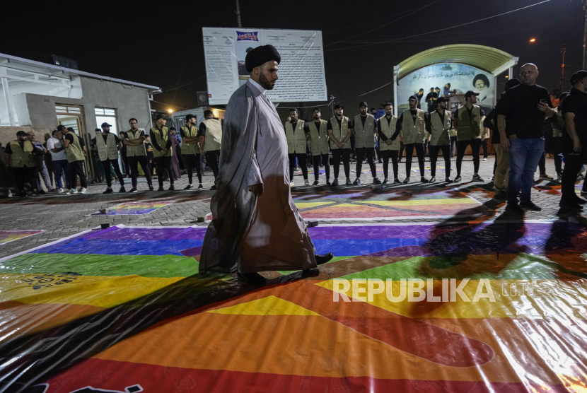 Pendukung ulama Moqtada Sadr melangkah di atas bendera LGBTQ, saat unjuk rasa menentang pembakaran Alquran, 12 Juli 2023.