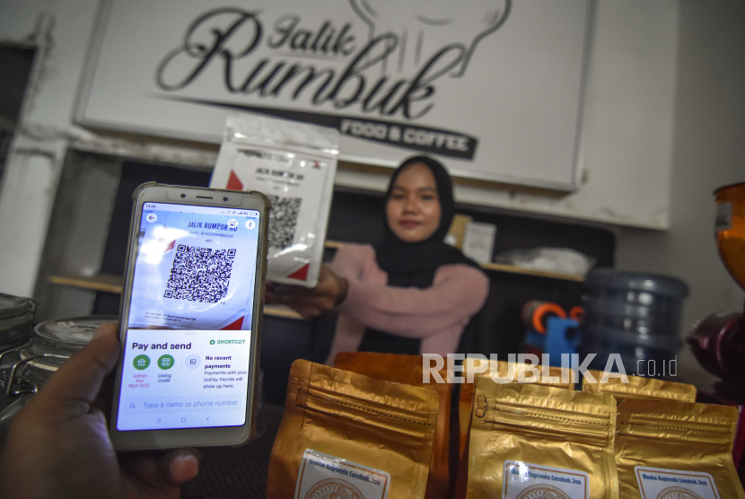Seorang warga menggunakan pembayaran nontunai Quick Response Indonesia Standard (QRIS) saat membeli kopi di warung kopi Jalik Rumbuk di Mataram, NTB, Selasa (12/1/2021). Menurut data Bank Indonesia (BI) pada tahun 2020 sebanyak 5,8 juta merchant secara nasional dan hampir semuanya Usaha Mikro, Kecil dan Menengah (UMKM) telah terhubung dengan alat pembayaran QRIS dan BI menargetkan pada tahun 2021 sebanyak 12 juta UMKM akan mulai masuk dalam ekosistem digitalisasi  serta terhubung dengan alat pembayaran QRIS yang memungkinkan adanya transaksi tanpa tatap muka sehingga pembayaran bisa berlangsung cepat, mudah, aman dan andal. 