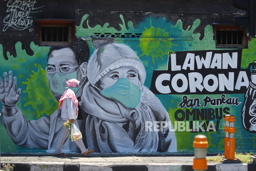 Warga melintas di depan mural Lawan Corona di Jalan Wonokromo, Surabaya, Jawa Timur. Tim peneliti di kampus Unair mengklaim telah memiliki obat Covid-19. Obat dibuat Unair bersama BIN, TNI AD, dan BPOM.