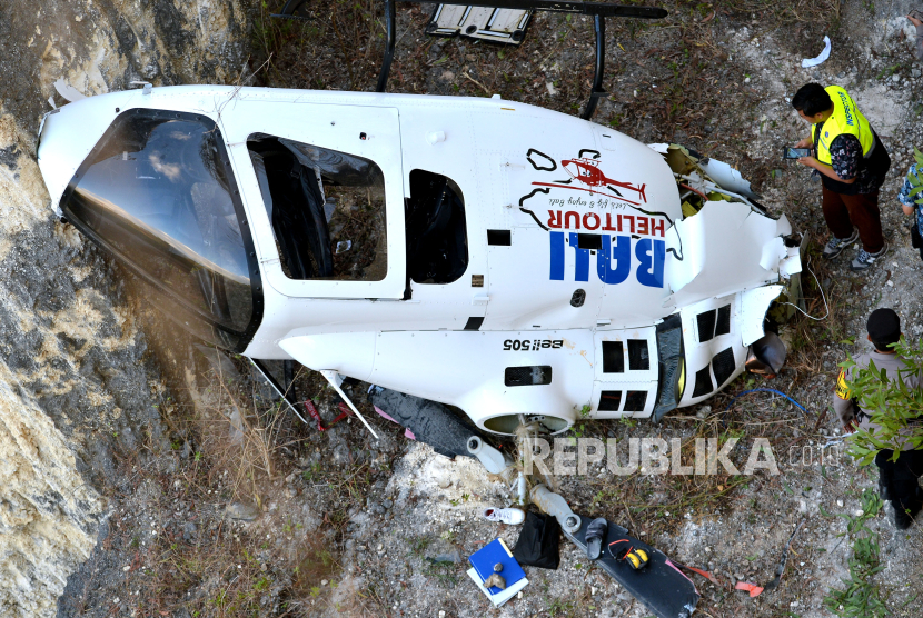 Petugas memeriksa helikopter Bell-505 yang dioperasikan PT. Whitesky Aviation setelah jatuh di kawasan Suluban, Badung, Bali, Jumat (19/7/2024). Helikopter tur wisata dengan nomor registrasi PK-WSP tersebut melakukan upaya pendaratan darurat dan mengalami kecelakaan karena terlilit tali layangan yang mengakibatkan seorang pilot dan empat penumpangnya terluka. 