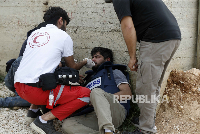  Pekerja medis Palestina membantu seorang jurnalis yang terluka saat bentrok dengan pasukan Israel setelah protes terhadap pemukim Israel yang berunjuk rasa di dekat pos terdepan Avitar, dekat desa Beita di Tepi Barat, Senin (10/4/2023). Dua puluh lima warga Palestina terluka dalam bentrokan tersebut, warga Palestina kata kementerian kesehatan.
