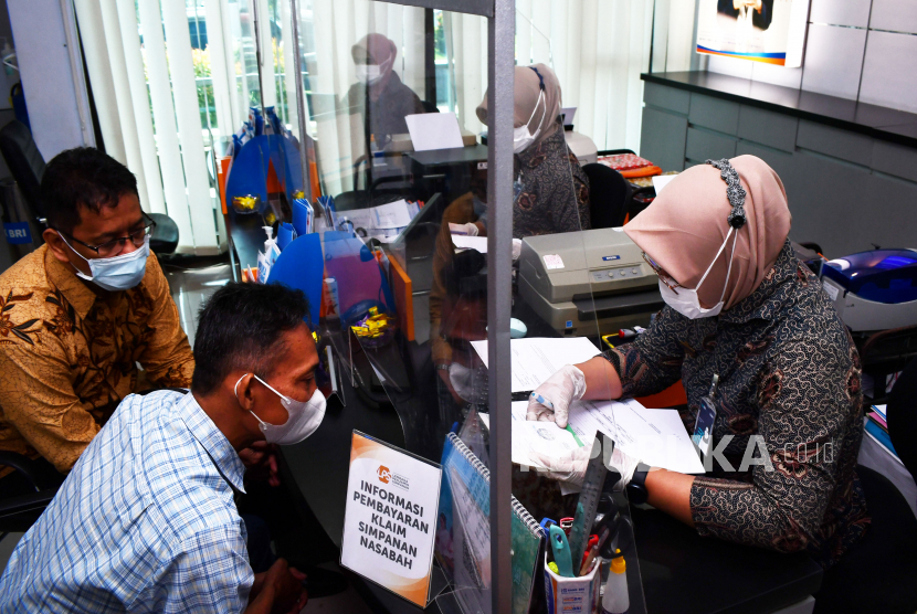 Ketua Dewan Komisioner Lembaga Penjamin Simpanan (LPS) Purbaya Yudhi Sadewa (kiri) memantau proses pembayaran klaim simpanan nasabah Bank Perkreditan Rakyat (BPR) Utomo Widodo di Kantor Cabang BRI Ngawi, Jawa Timur, Kamis (9/12/2021). LPS membayar klaim simpanan nasabah BPR Utomo Widodo menyusul pencabutan izin usaha BPR tersebut oleh Otoritas Jasa Keuangan (OJK). 