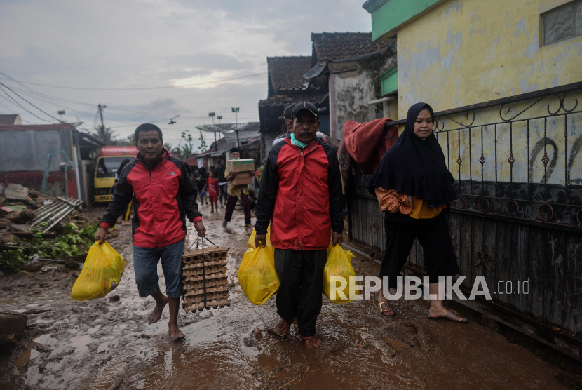 Warga membawa sembako bantuan korban banjir  bandang di Kampung Cibuntu, Desa Pasawahan, Kecamatan Cicurug, Kabupaten Sukabumi, Jawa Barat. Saat warga korban banjir banyak yang mengeluhkan mengalami ISPA dan gatal-gatal. (ilustrasi)