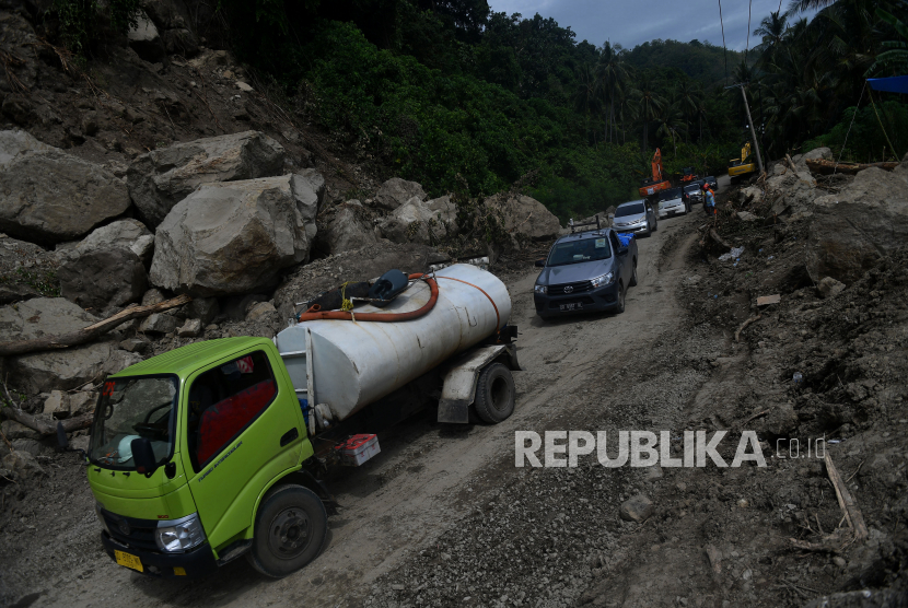 Sejumlah kendaraan melintas di Jalan Trans Sulawesi Poros Majene-Mamuju yang terkena longsor di Majene, Sulawesi Barat, Rabu (20/1/2021). Jalur yang sempat terputus akibat longsor tersebut sudah bisa dilalui dengan sistem buka tutup arus kendaraan dari dua arah. 