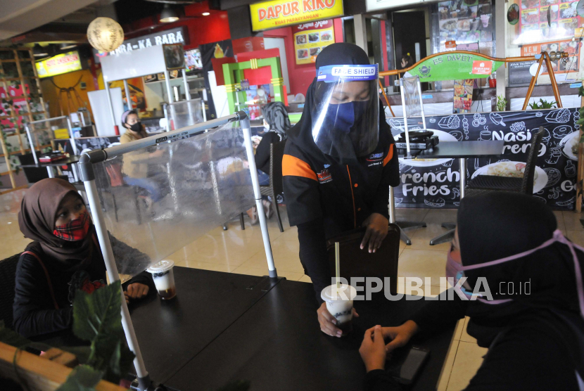 Petugas menyajikan makanan di restoran mal Bekasi Cyber Park , Jawa Barat, Ahad (7/6/2020). Sejumlah tempat makan mulai menerapkan protokol kesehatan untuk pengunjung yang makan di tempat guna mencegah penyebaran wabah COVID-19