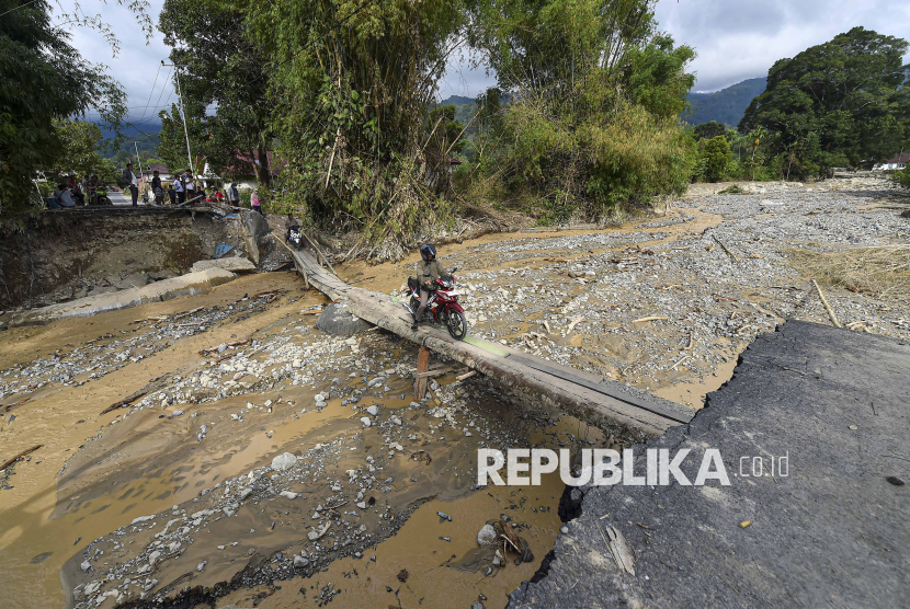 Pengendara sepeda motor menyeberangi jembatan darurat  di Tanjung Raya, Agam, Sumatera Barat, Jumat (5/12/2025). Akses jalan darat di kawasan sekeliling Danau Maninjau yang sempat terputus akibat banjir bandang di lima titik pada Kamis (27/12) lalu saat ini telah bisa dilalui menggunakan sepeda motor. 