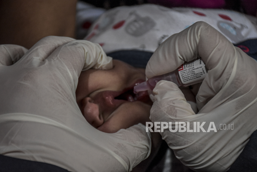 Petugas kesehatan memberikan vaksin polio kepada seorang anak.