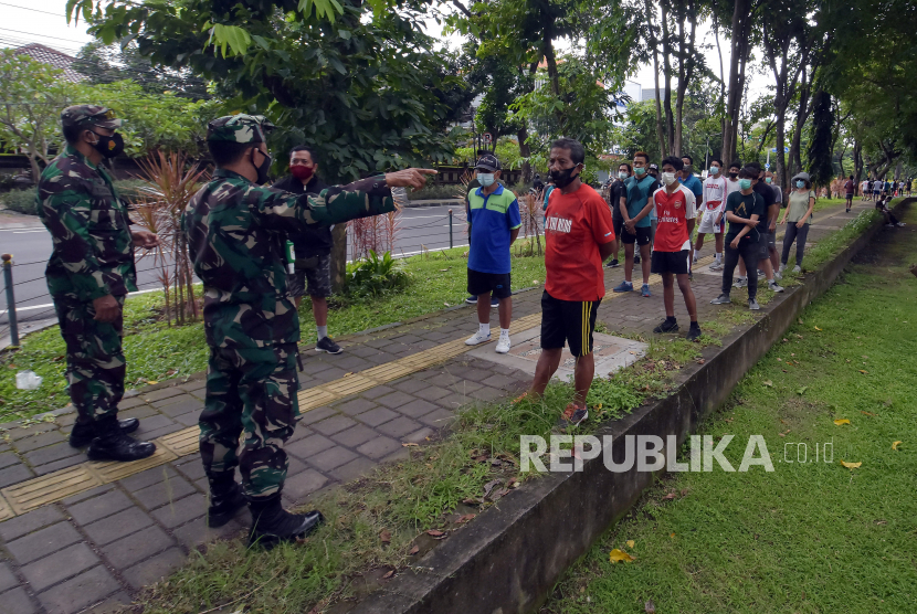 Anggota TNI AD menegur puluhan warga saat penutupan ruang publik di Lapangan Puputan Margarana Renon, Denpasar, Bali, Selasa (2/2/2021). Kegiatan tersebut untuk menertibkan warga agar tidak beraktivitas di ruang publik yang ditutup sementara selama Pemberlakuan Pembatasan Kegiatan Masyarakat (PPKM) untuk mencegah kerumunan dan menekan penyebaran COVID-19. 