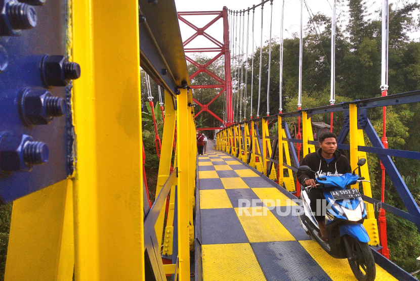 Warga melintas di Jembatan Gantung Mangunsuko, Dukun, Magelang, Jawa Tengah, Selasa (21/7). Jembatan gantung ini lebih  dikenal dengan nama Jembatan Jokowi. Pasalnya, pada waktu itu diresmikan oleh Presiden Joko Widodo. Dan kini jembatan yang dicat warna-warni ini menjadi daya tarik wisata baru di sini.