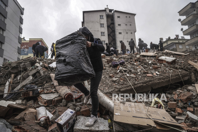  Orang-orang dan tim penyelamat mencari korban gempa di puing-puing di sebuah bangunan yang hancur di Gaziantep, Turki, Senin (6/2/2023). Gempa kuat telah merobohkan beberapa bangunan di tenggara Turki dan Suriah dan dikhawatirkan banyak korban jiwa.