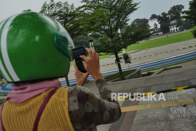 Lapangan Gasibu dan Saparua Bandung Dibuka untuk Umum. Seorang penumpang ojol berhenti sejenak untuk memotret Lapang Gasibu Bandung, Kamis (20/5). Setahun terakhir salah satu landmark kota Bandung ini ditutup untuk umum akibat pandemi.