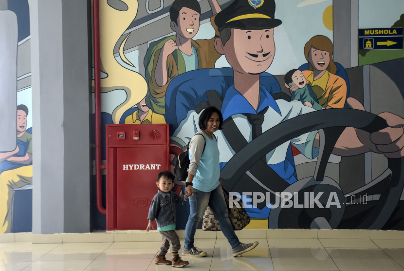 Calon penumpang berjalan di depan mural di Terminal Leuwipanjang, Bandung, Jawa Barat, Jumat (8/12/2023). 