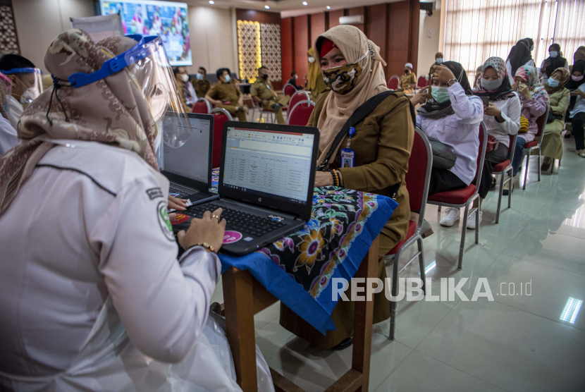 Petugas kesehatan membantu mengisi formulir sebelum menyuntikkan vaksin COVID-19 kepada tenaga pendidikan di Palembang, Sumatera Selatan, Senin (8/3/2020). Sebagai upaya menekan penyebaran COVID-19 di lingkungan sekolah, Pemerintah Kota Palembang memulai tahap vaksinasi untuk 800 orang guru dan tenaga pendidik di wilayah tersebut. 