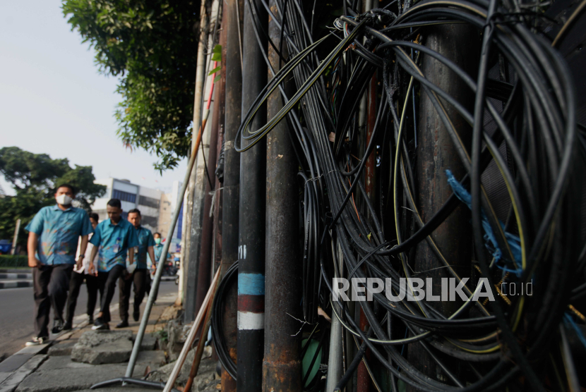 Warga berjalan di dekat kabel jaringan utilitas yang semrawut di kawasan Palmerah, Jakarta Barat. Kondisi korban kabel menjuntai, Sultan Rifat sudah mulai ada perkembangan di RS Polri