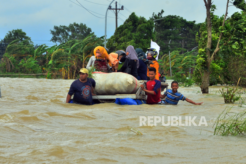 Relawan membantu warga melintasi jalan yang terendam banjir dengan perahu karet di Dusun Karangturi, Desa Setrokalangan, Kecamatan Kaliwungu, Kabupaten Kudus, Jawa Tengah, Senin (2/1/2023).