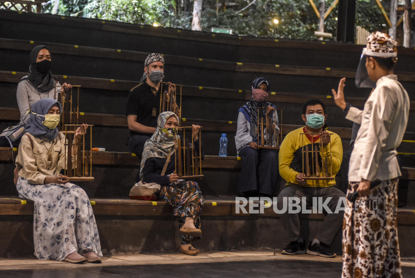 Sejumlah pengunjung mengenakan masker bermain angklung pada pertunjukan Bamboo Afternoon Show di Saung Angklung Udjo, Jalan Padasuka, Kota Bandung, Jawa Barat,beberapa waktu lalu. Akibat pandemi Covid-19 yang mengakibatkan tujunnya jumlah kunjungan, Saung Angklung Udjo terancam tutup.