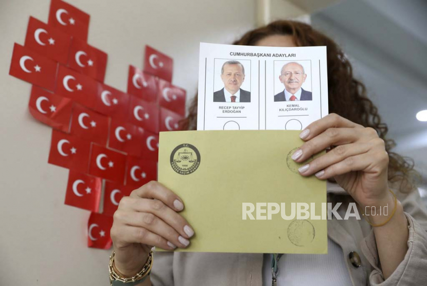Seorang petugas dari penyelenggara pemilu memperlihatkan surat suara dengan kandidat presiden di sebuah tempat pemungutan suara di Ankara, Turki, Ahad, (28/5/2023). 
